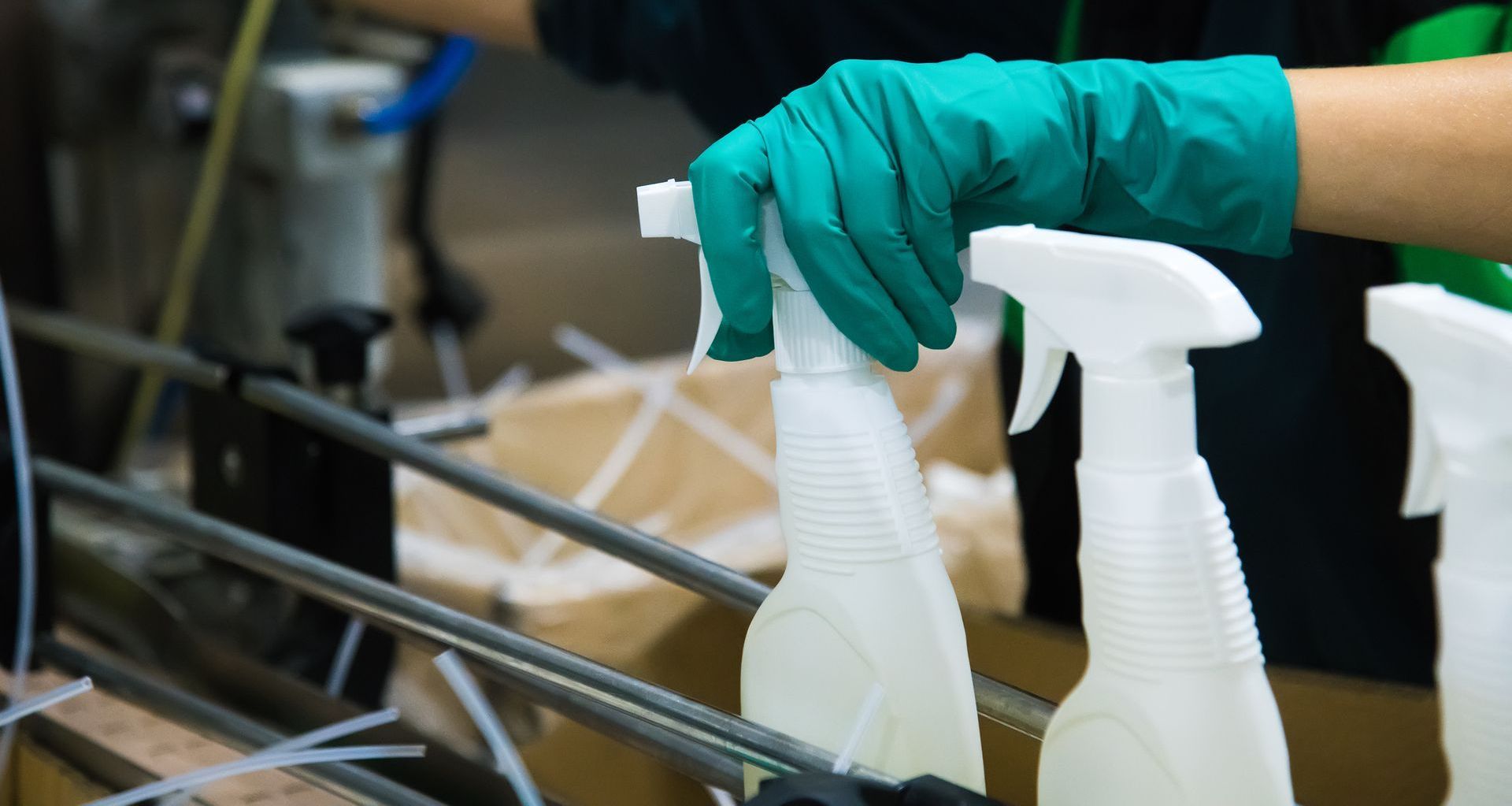 a person wearing green gloves tightens the sprayer cap a spray bottle