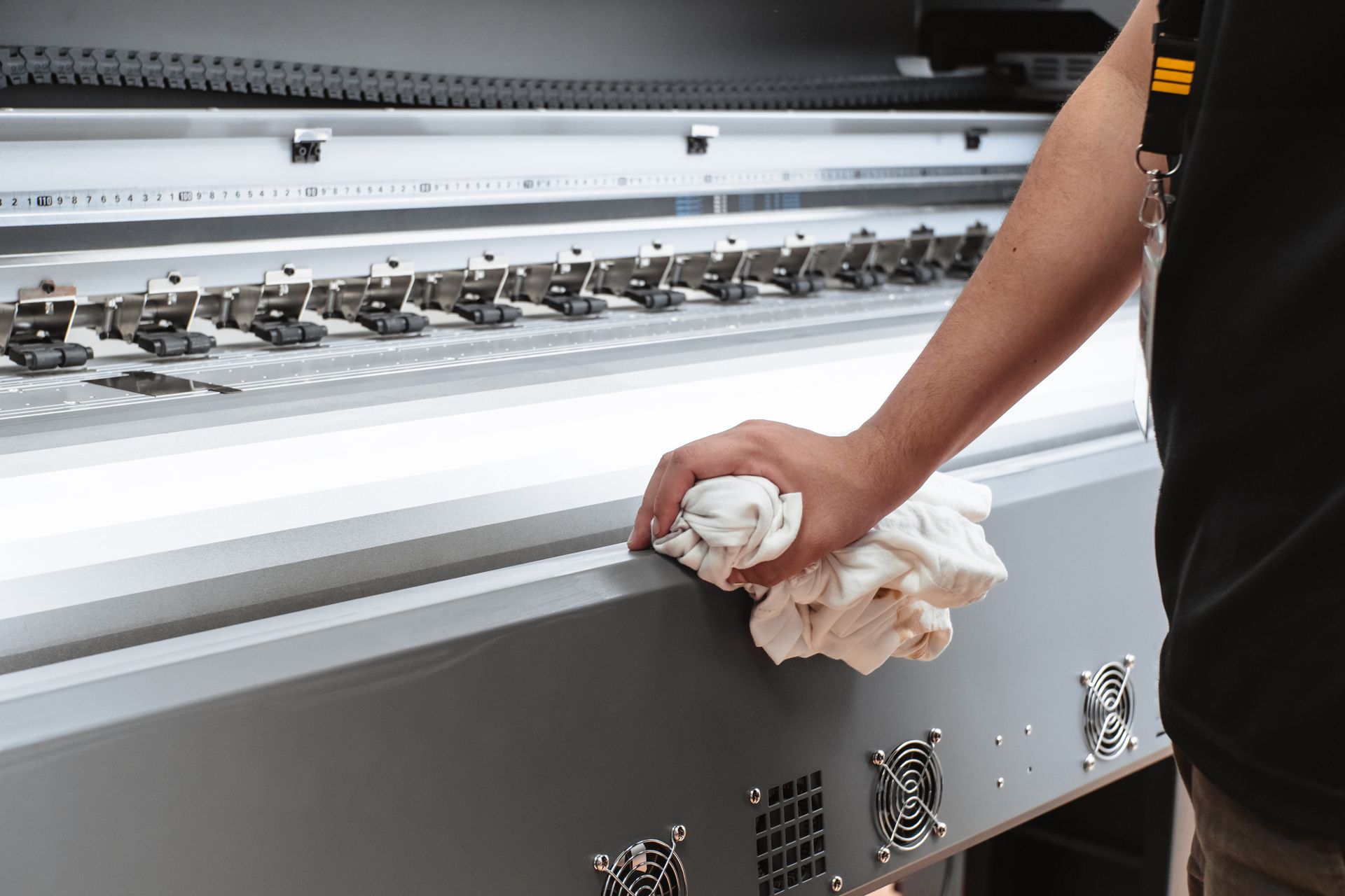 a man is cleaning printing press parts with a cloth