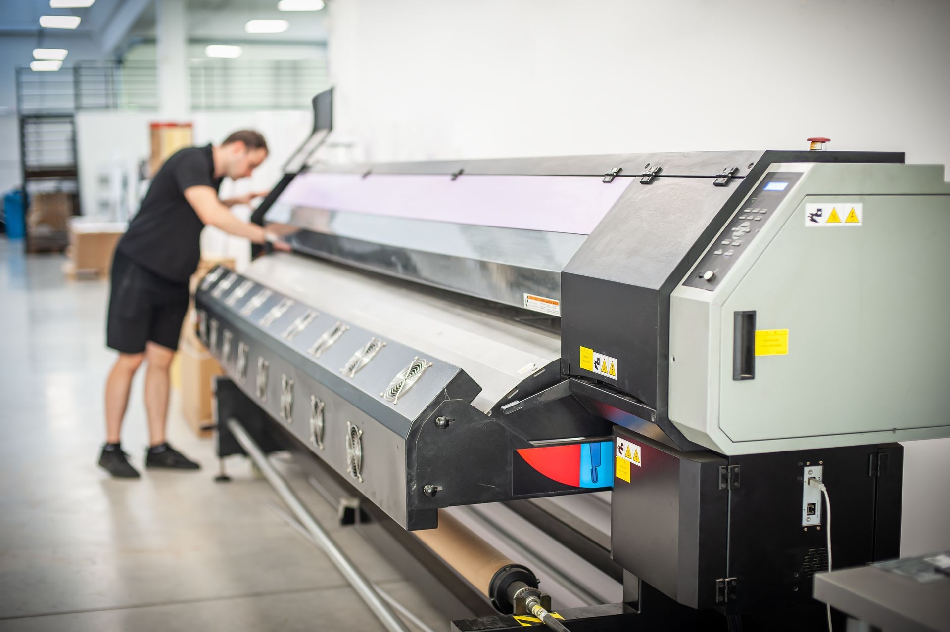 a man is working on a large printer in a factory, cleaning press parts