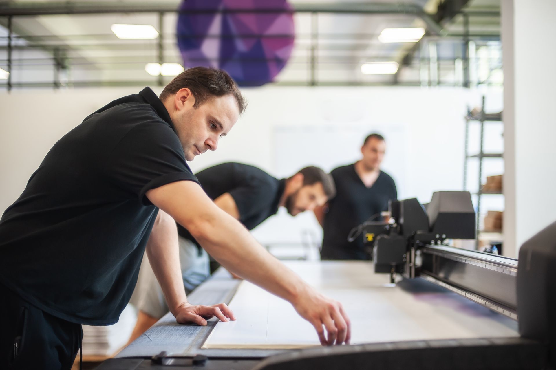 a group of men are working on a printing press in a factory
