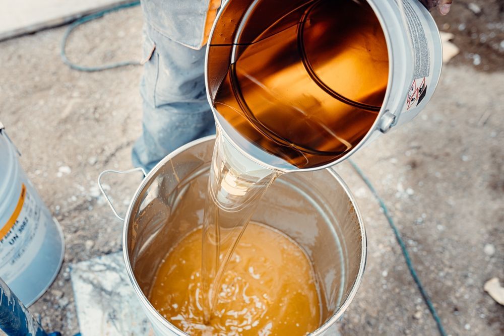 A person is pouring liquid into a bucket.