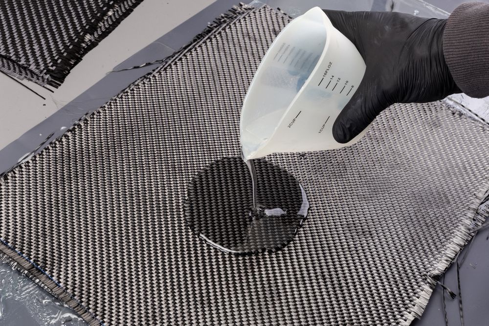 A person is pouring liquid from a measuring cup onto a piece of fabric.