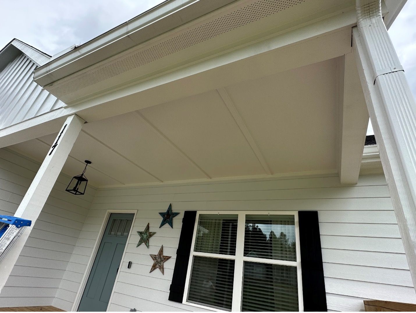 A white house with black shutters and stars on the front porch