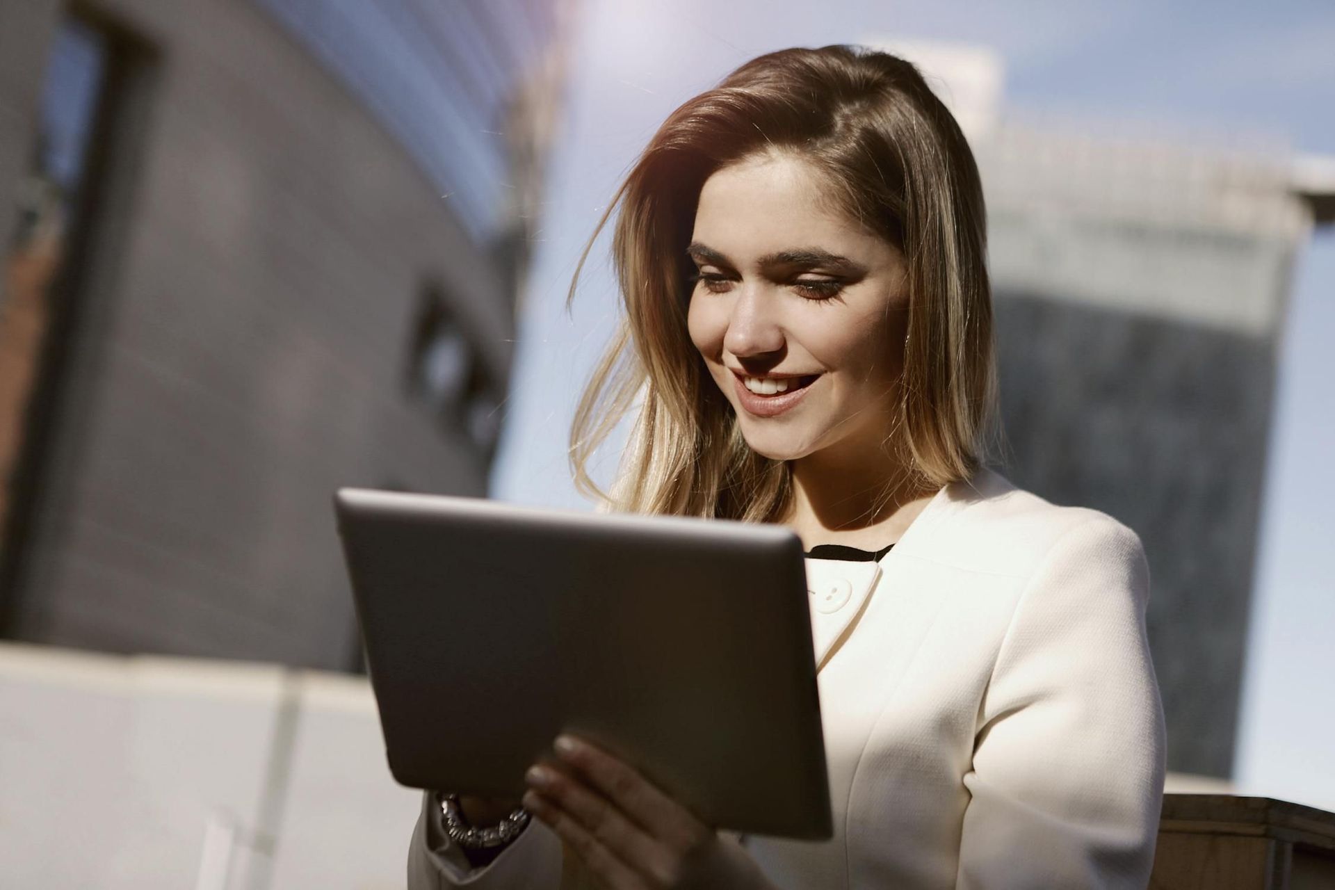 A woman is using a tablet computer outside in the city.