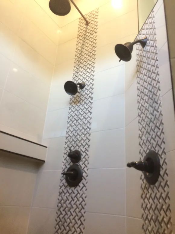 A shower with three shower heads and a patterned wall