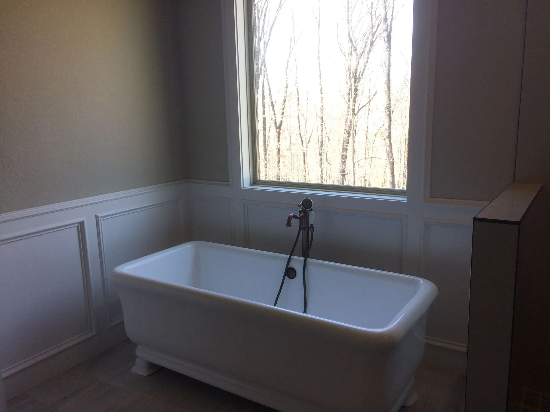 A bathtub in a bathroom next to a window.