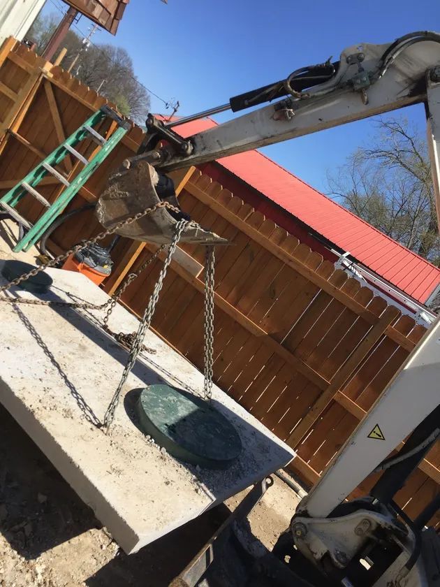 An excavator is lifting a concrete slab with chains attached to it