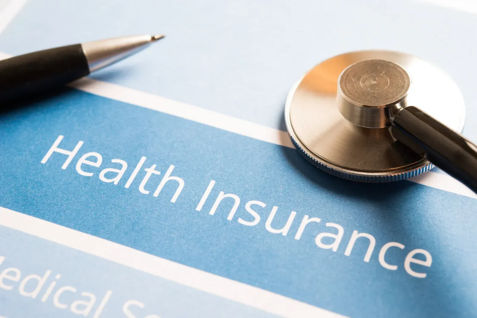 Health insurance form with a stethoscope and pen on a blue background