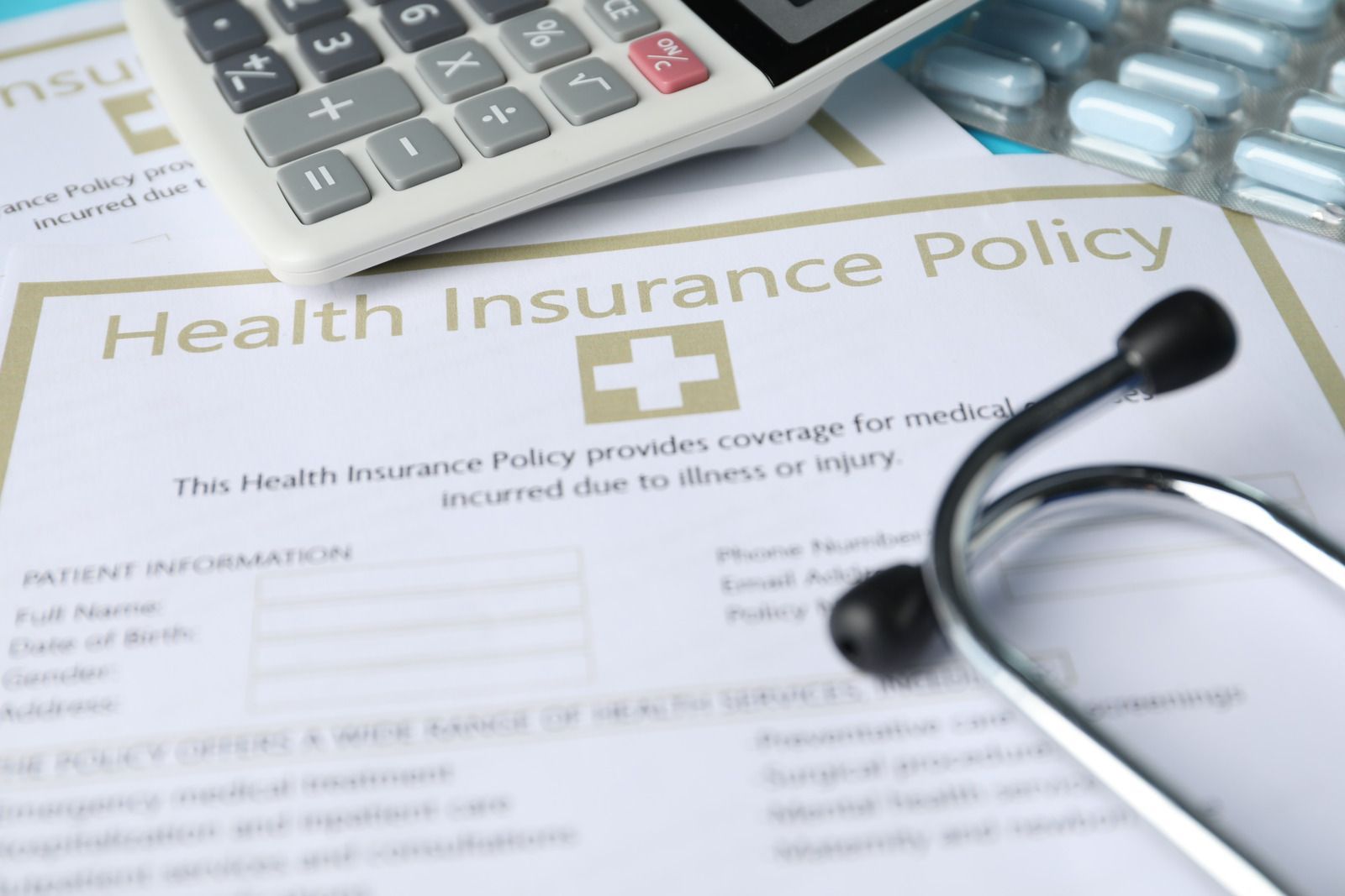 Health insurance policy form with stethoscope and calculator on a desk