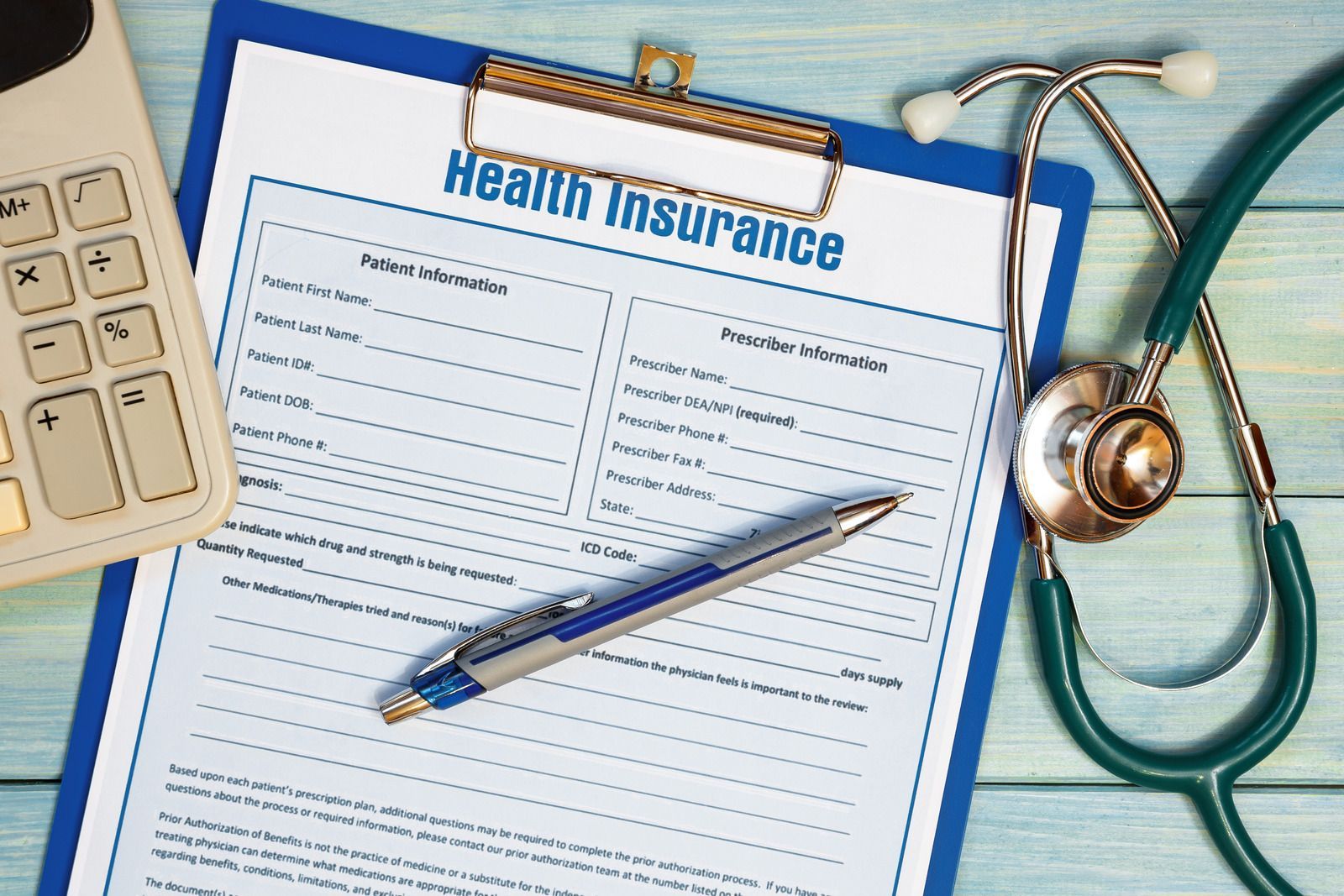 Health insurance form with pen, keyboard, and stethoscope on a desk