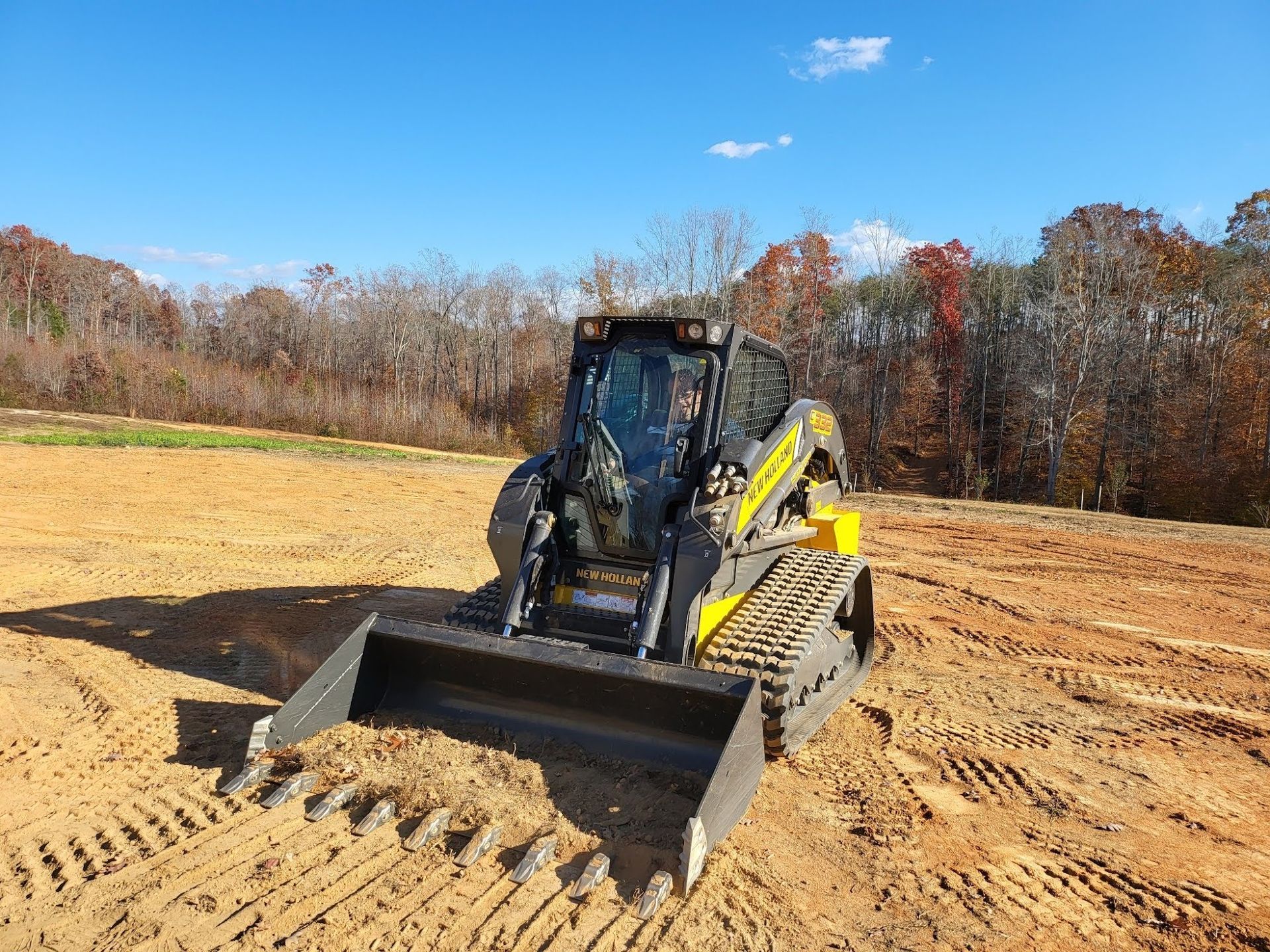 Yellow and black skid steer loader on a construction site with a blue sky.