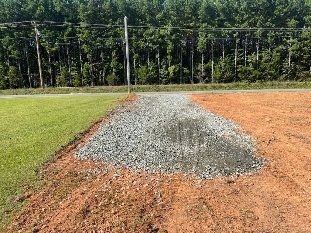 Gravel path being built next to grass and dirt, with trees in background.