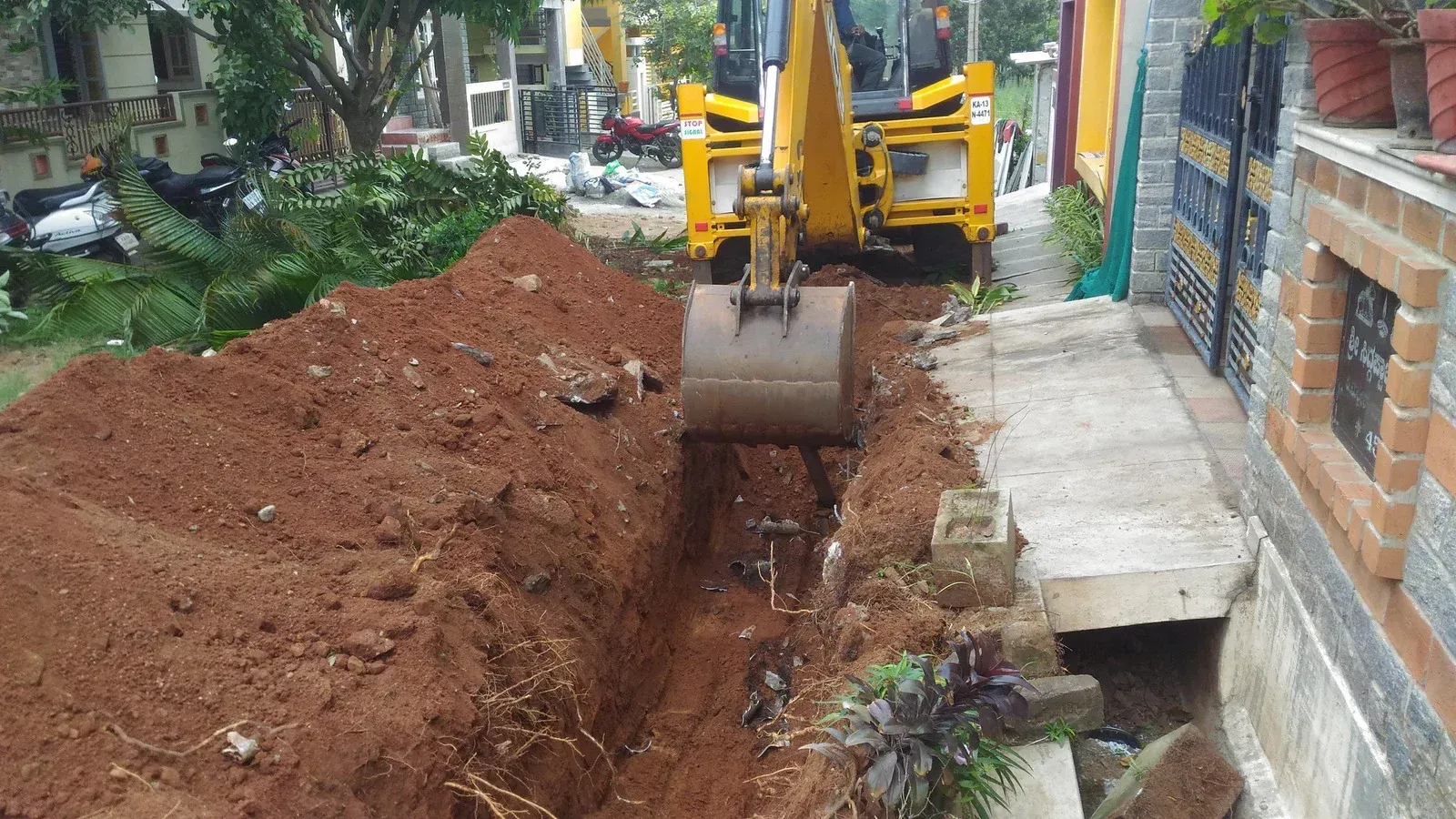 Construction site with trenches filled with white drainage pipes, surrounded by sand and dirt.