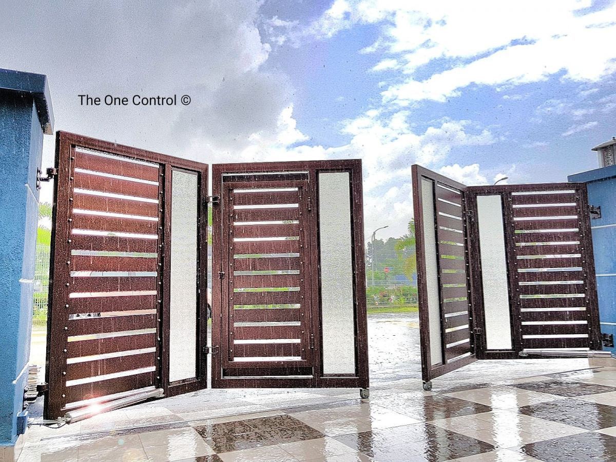 A brown wooden-slat folding autogate opening on a wet tiled driveway,
