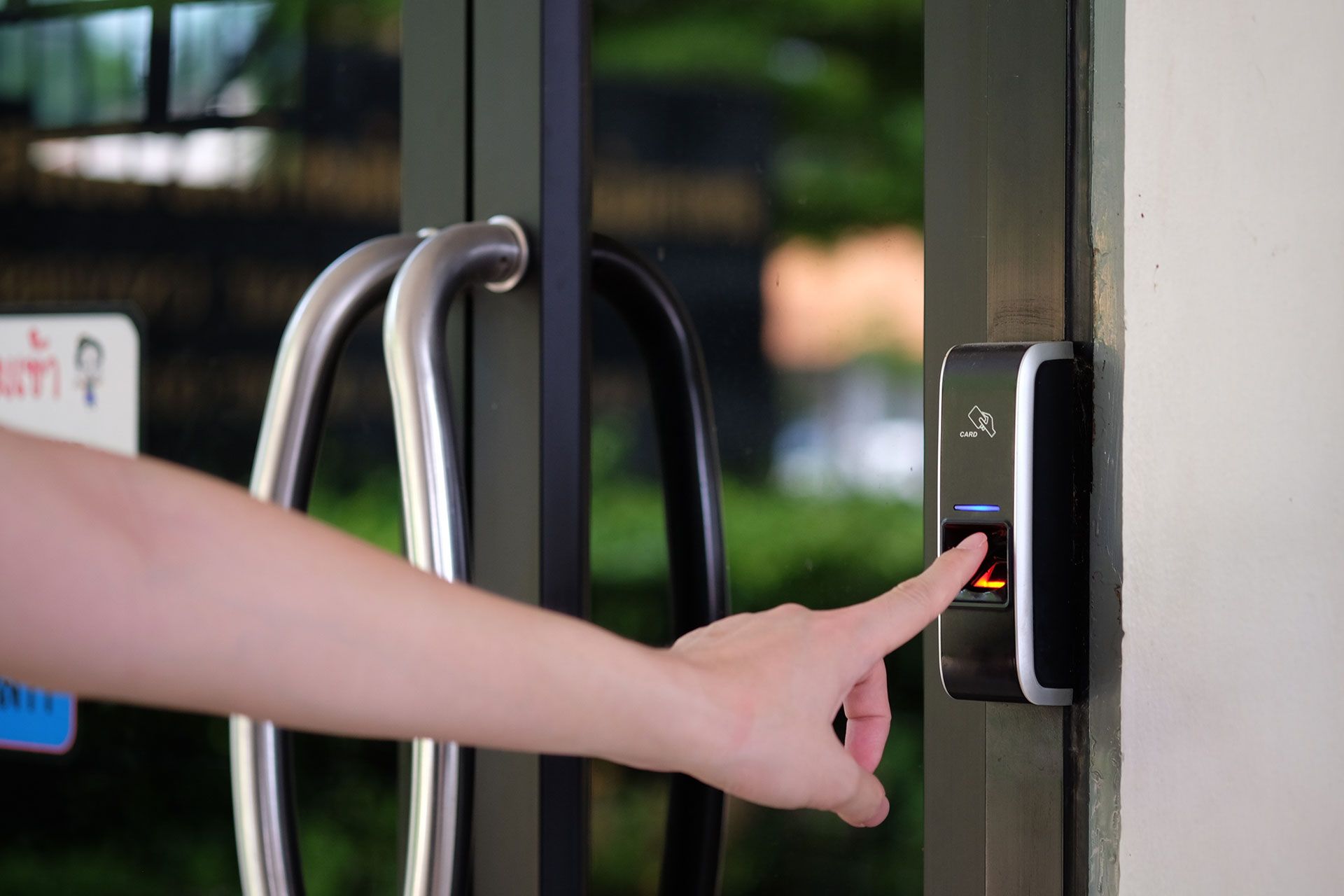 Employee scanning fingerprint on a biometric reader installed by a door access system company.