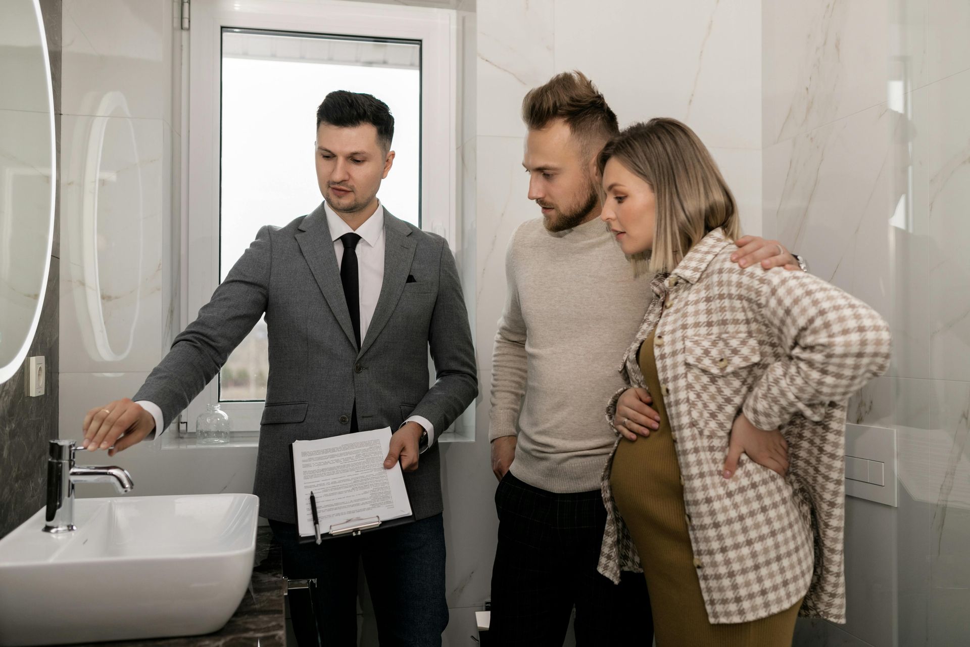 A man is standing next to a pregnant woman and a man in a bathroom.