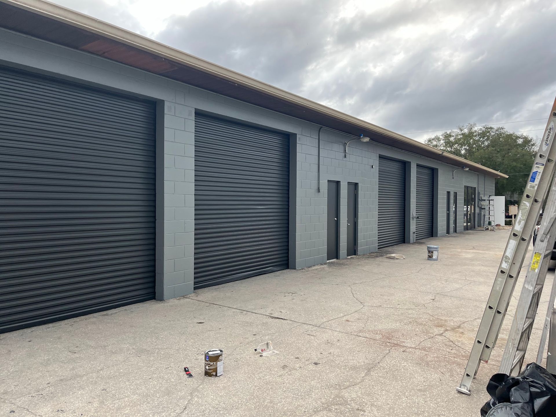 A row of garage doors are being painted on a building.