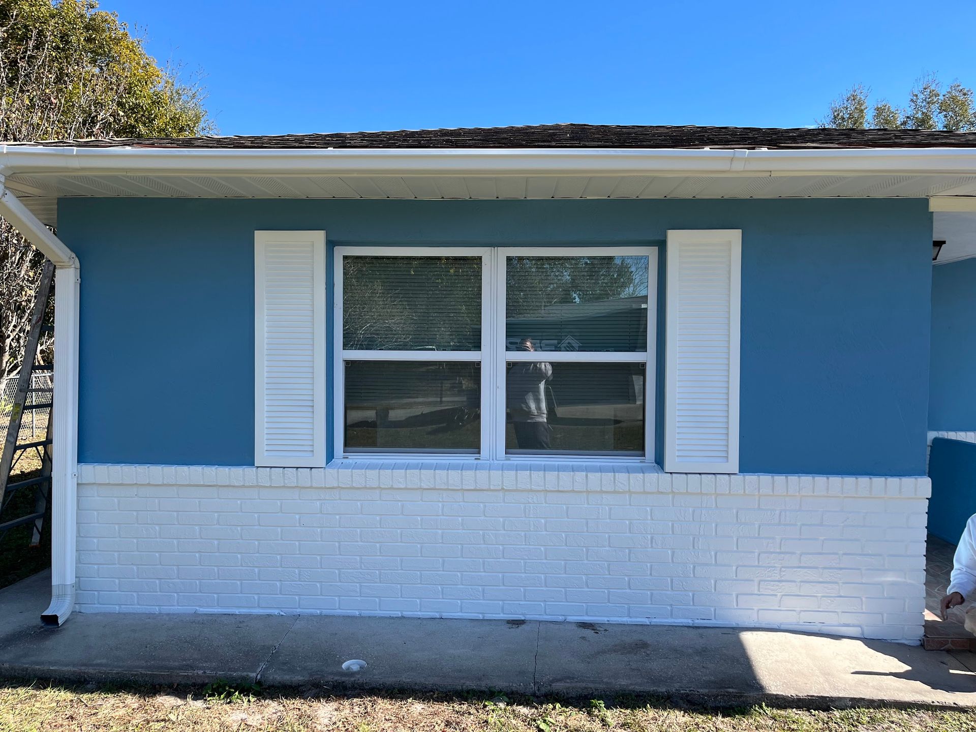 A blue and white house with white shutters on the windows.