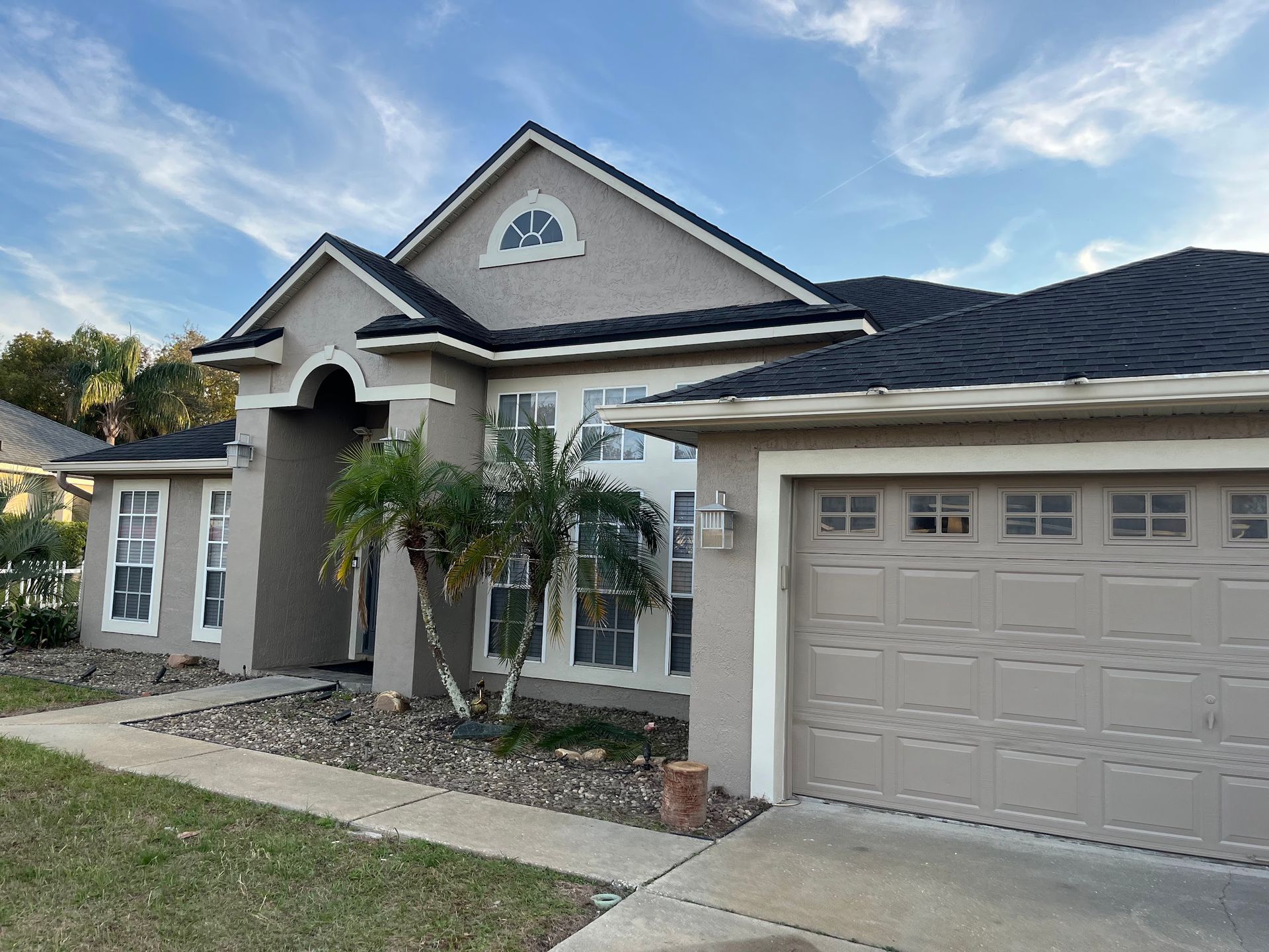 A house with a garage and a palm tree in front of it