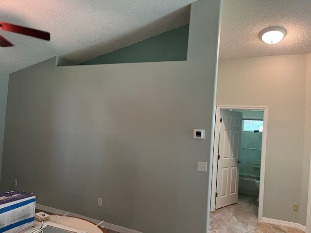 A living room with a ceiling fan and a doorway leading to a bathroom.