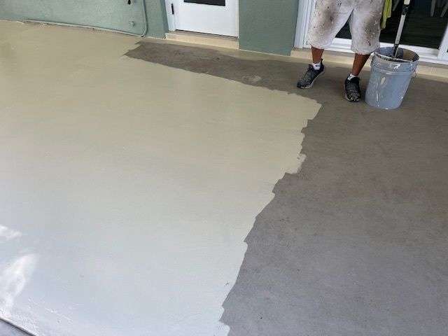 A man is painting a floor with a bucket of paint.