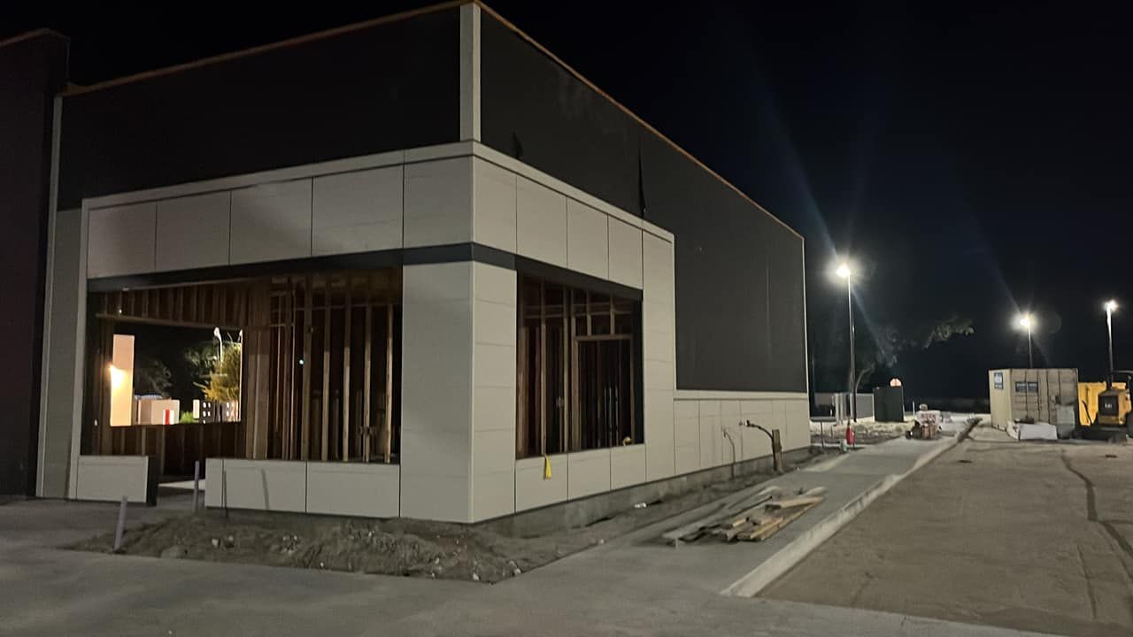 A building under construction is lit up at night.