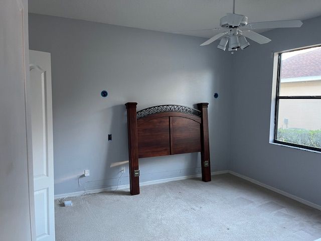Empty bedroom with gray walls, a brown headboard, and a window.
