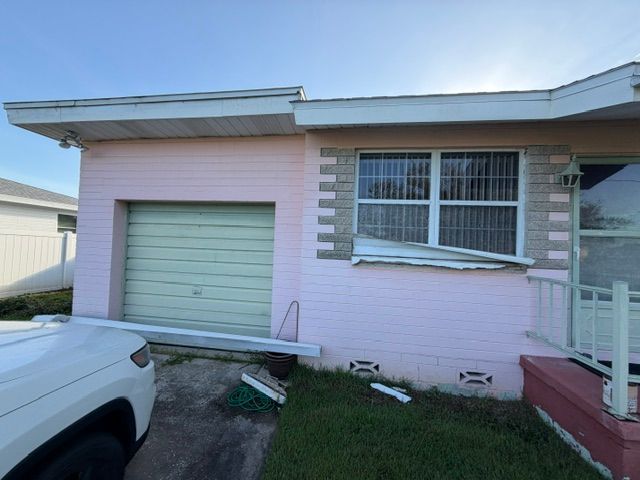 A before picture of a house with a palm tree in front of it.