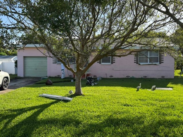 A before picture of a house with a red garage door.