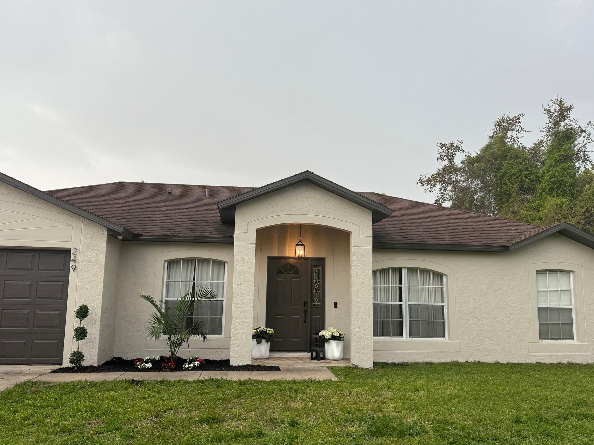 A white house with a brown roof and a porch