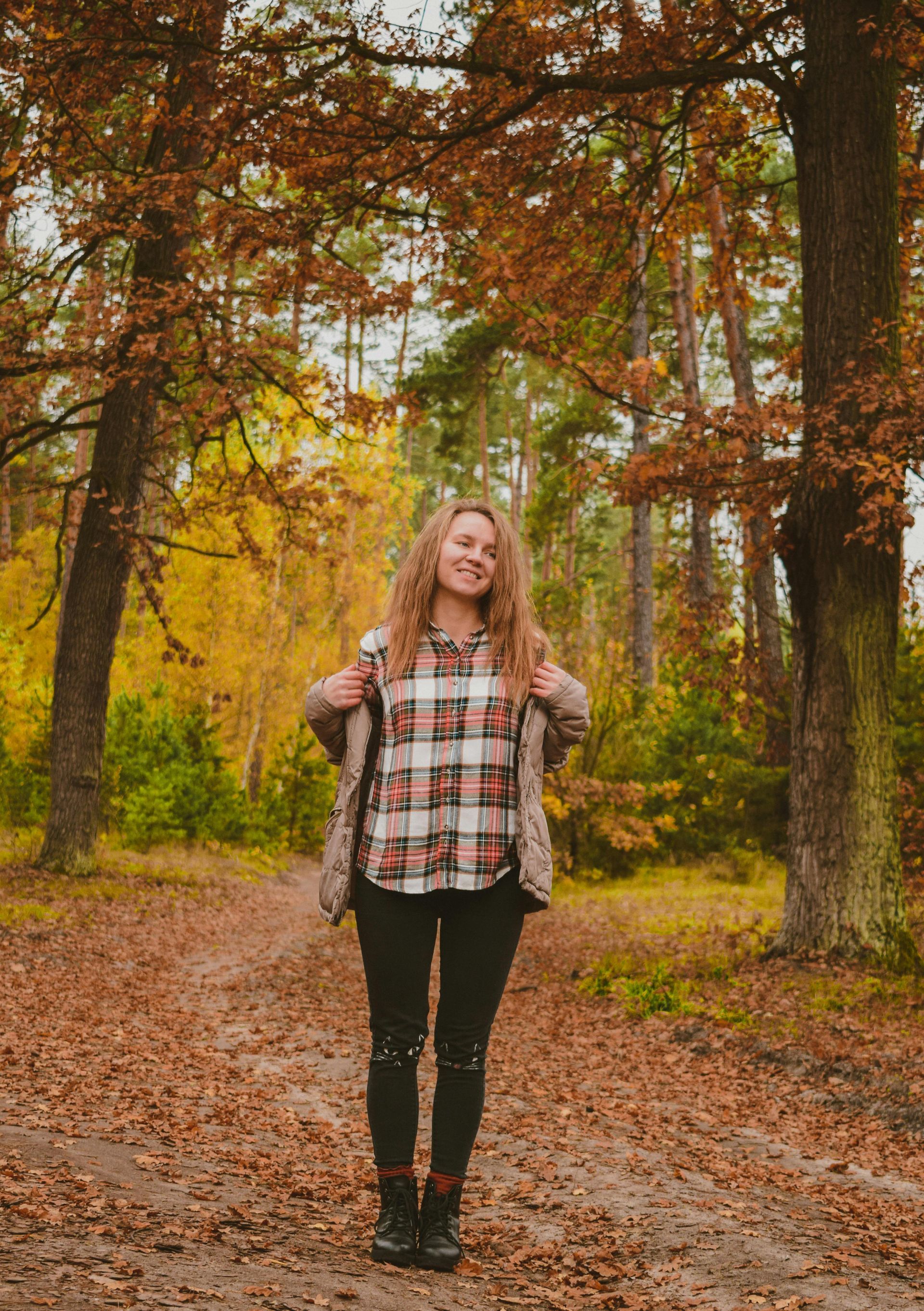 A woman is standing on a path in the woods.