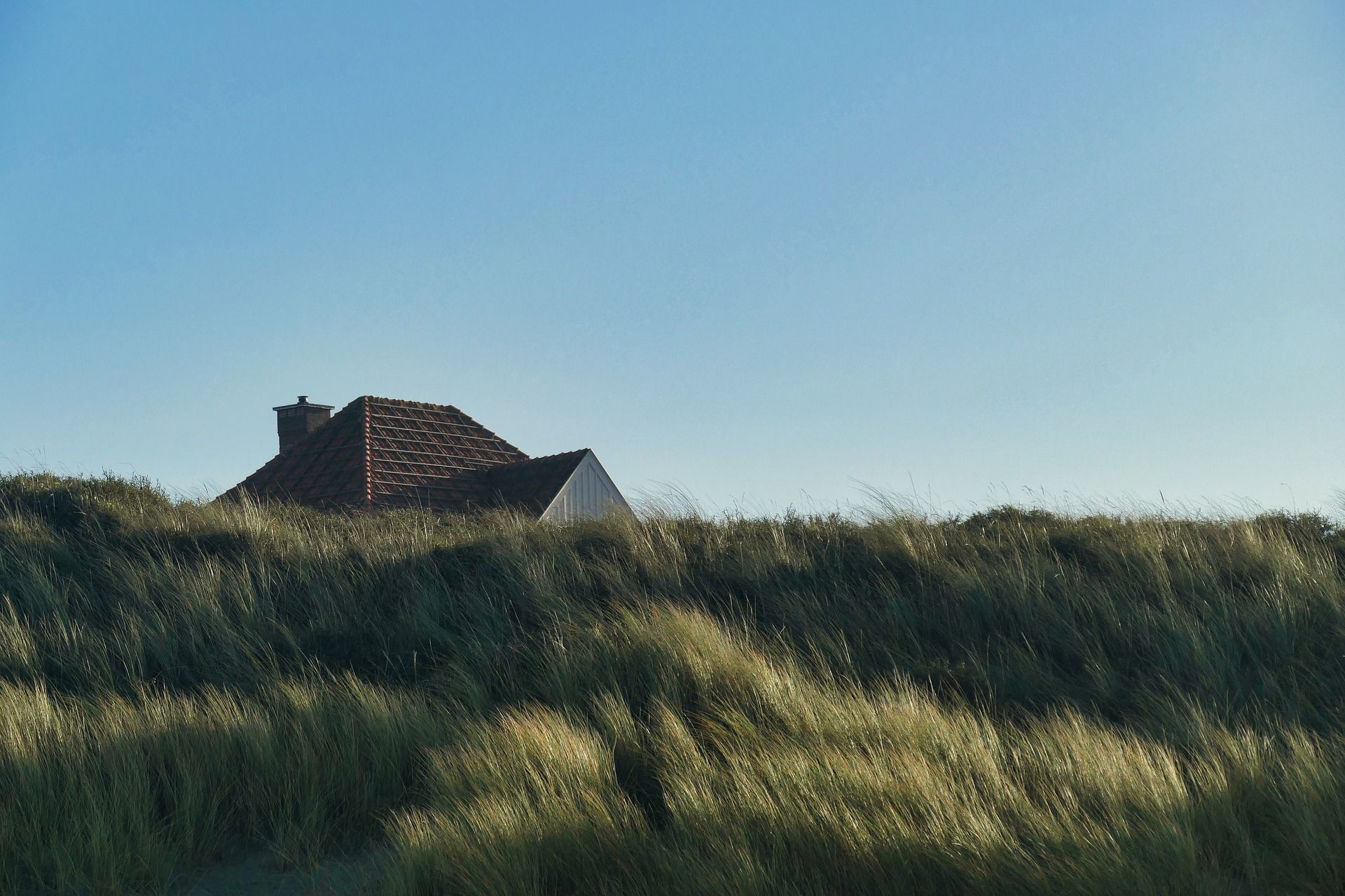 A house is sitting on top of a grassy hill.