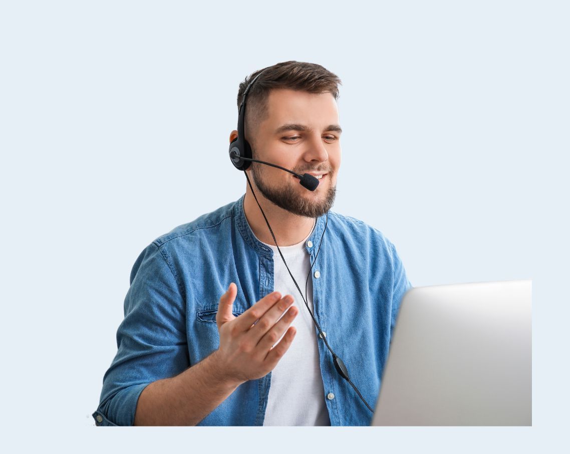 Man wearing a headset speaking beside a laptop against a light background