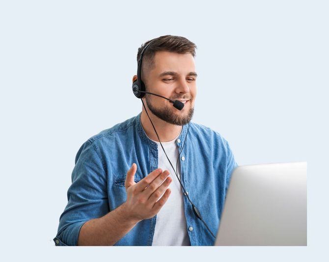 Man wearing a headset speaking beside a laptop against a light background