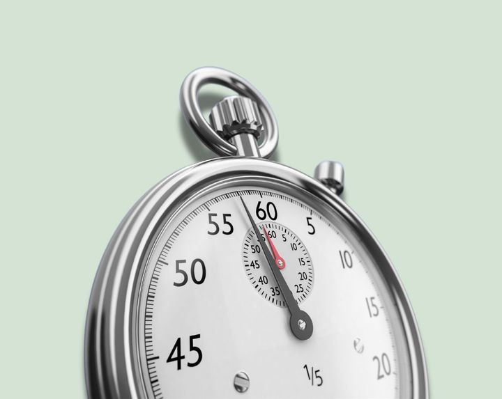 Close-up of a silver stopwatch with the second hand near 60 on a pale green background