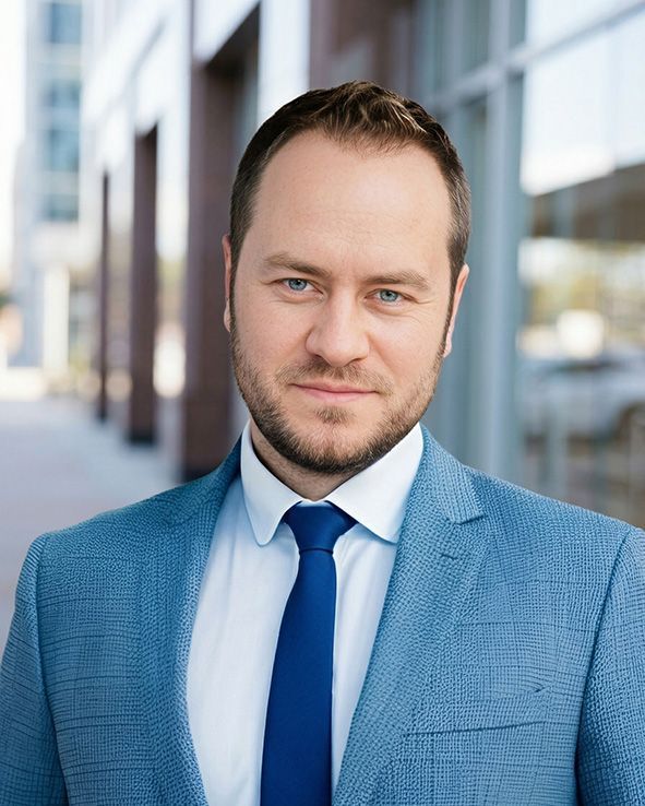 Man in blue suit and tie standing outdoors in a bright urban setting