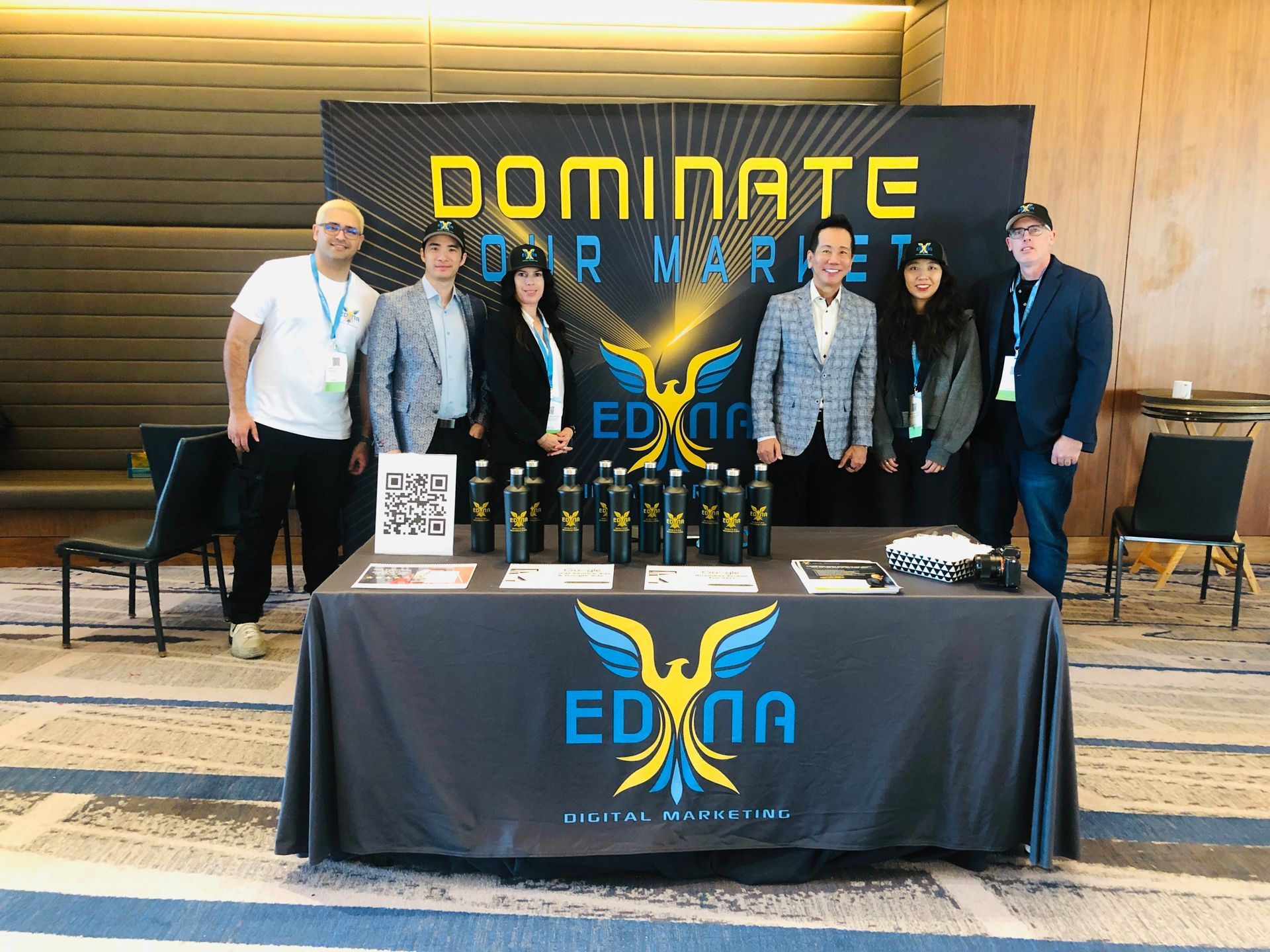 Five people at an EDNA booth with trophies and a “Dominate Your Market” banner behind them.