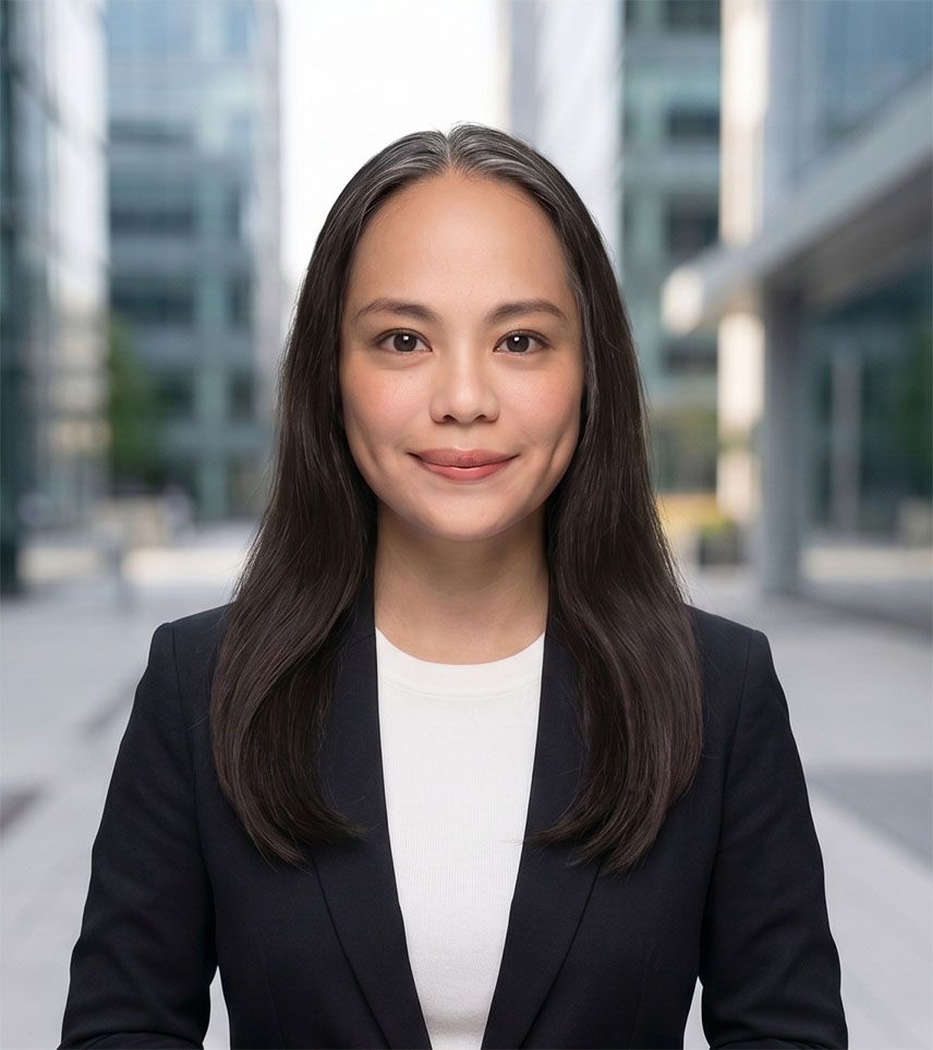 Professional portrait of a woman in a dark blazer, standing outdoors in a modern city setting