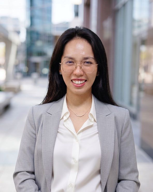 Smiling professional in a light gray blazer and white blouse standing outdoors in a city setting