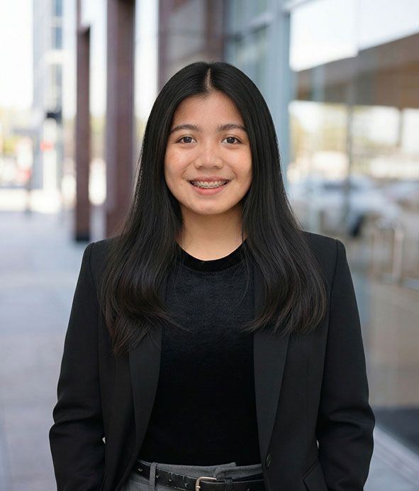 Smiling woman in a black blazer standing outdoors against a blurred building background