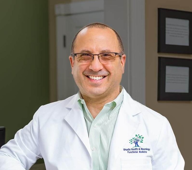 Smiling doctor in white coat standing in a clinic hallway