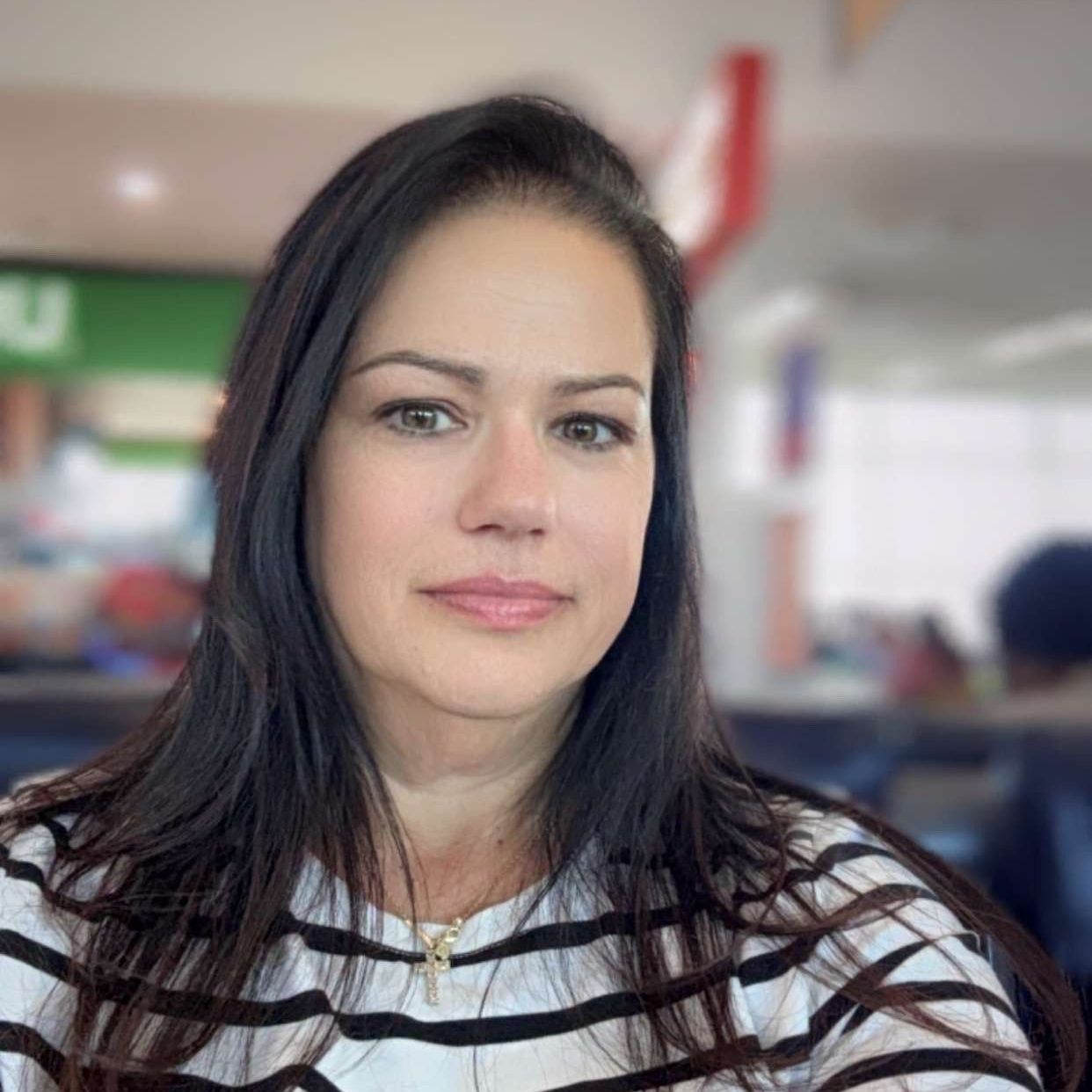 A woman with long hair is wearing a striped shirt and looking at the camera.