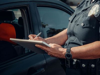 A woman is sitting in the back seat of a car holding a cell phone.