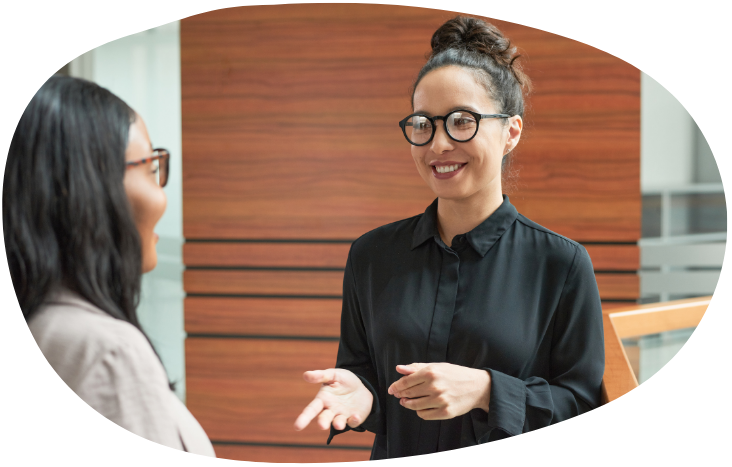 Two people talking in an office, one gesturing while smiling.