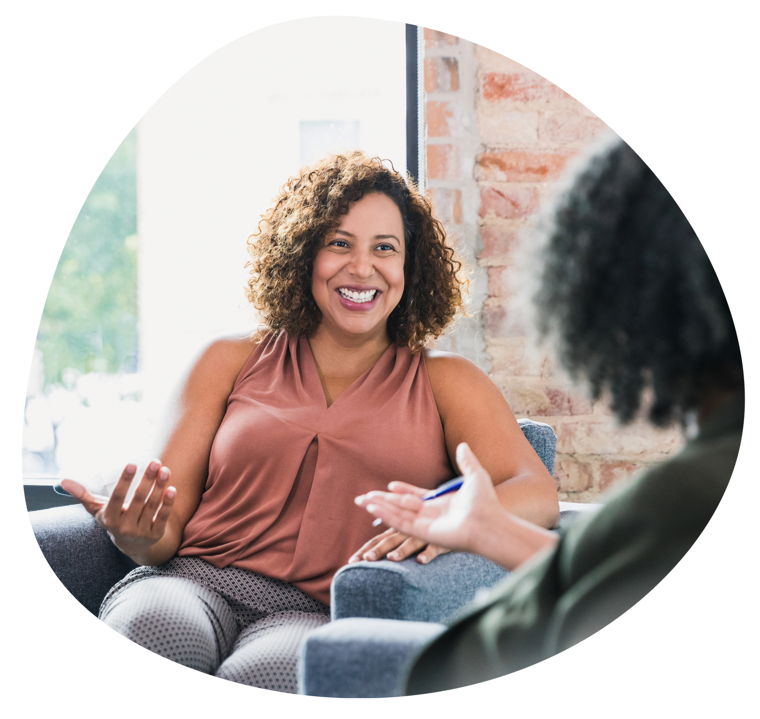 Smiling woman in a pink top talking with someone in a bright living room