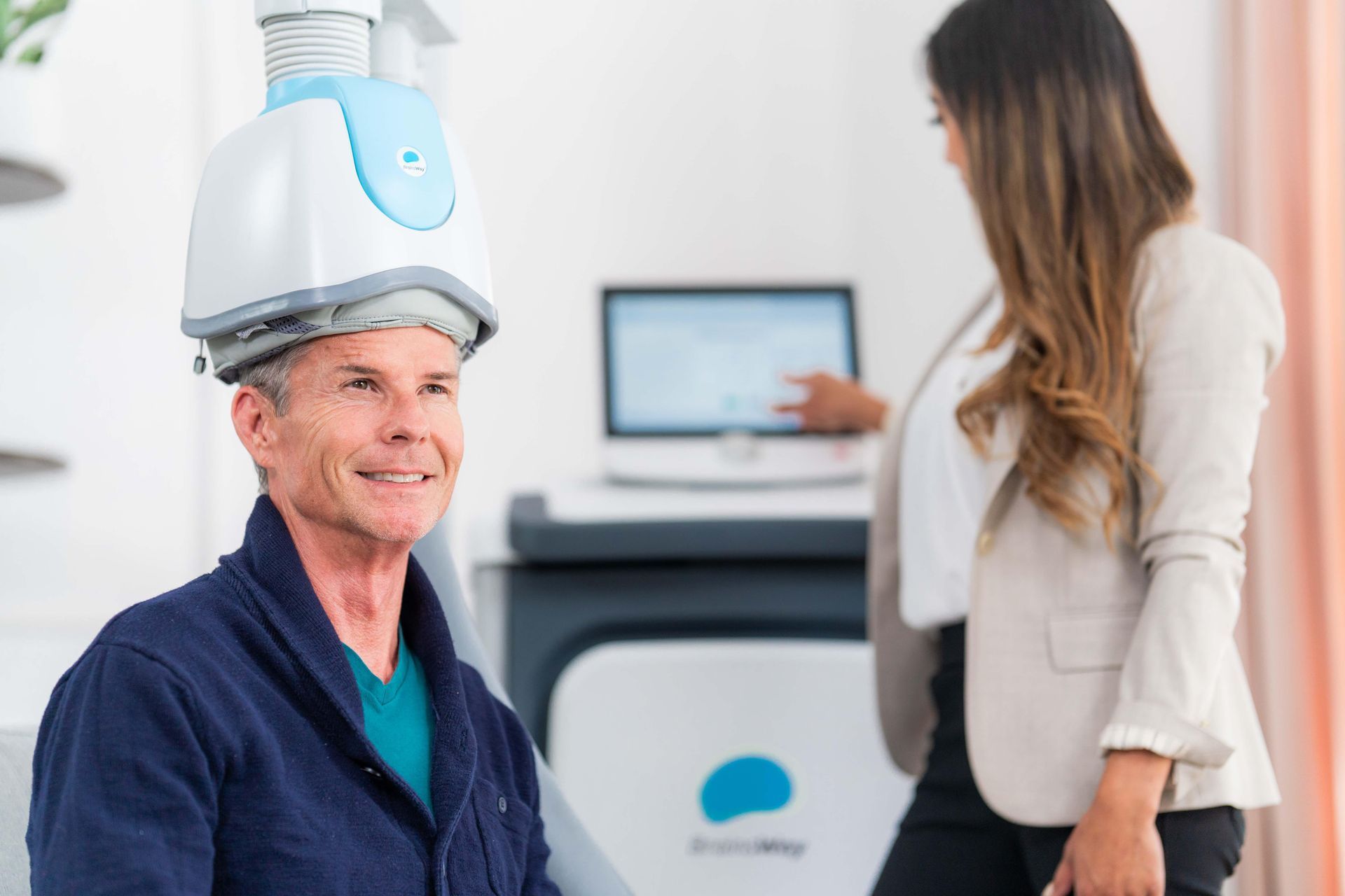 Person wearing a head-mounted scanner in a clinic while another person operates a medical device in the background