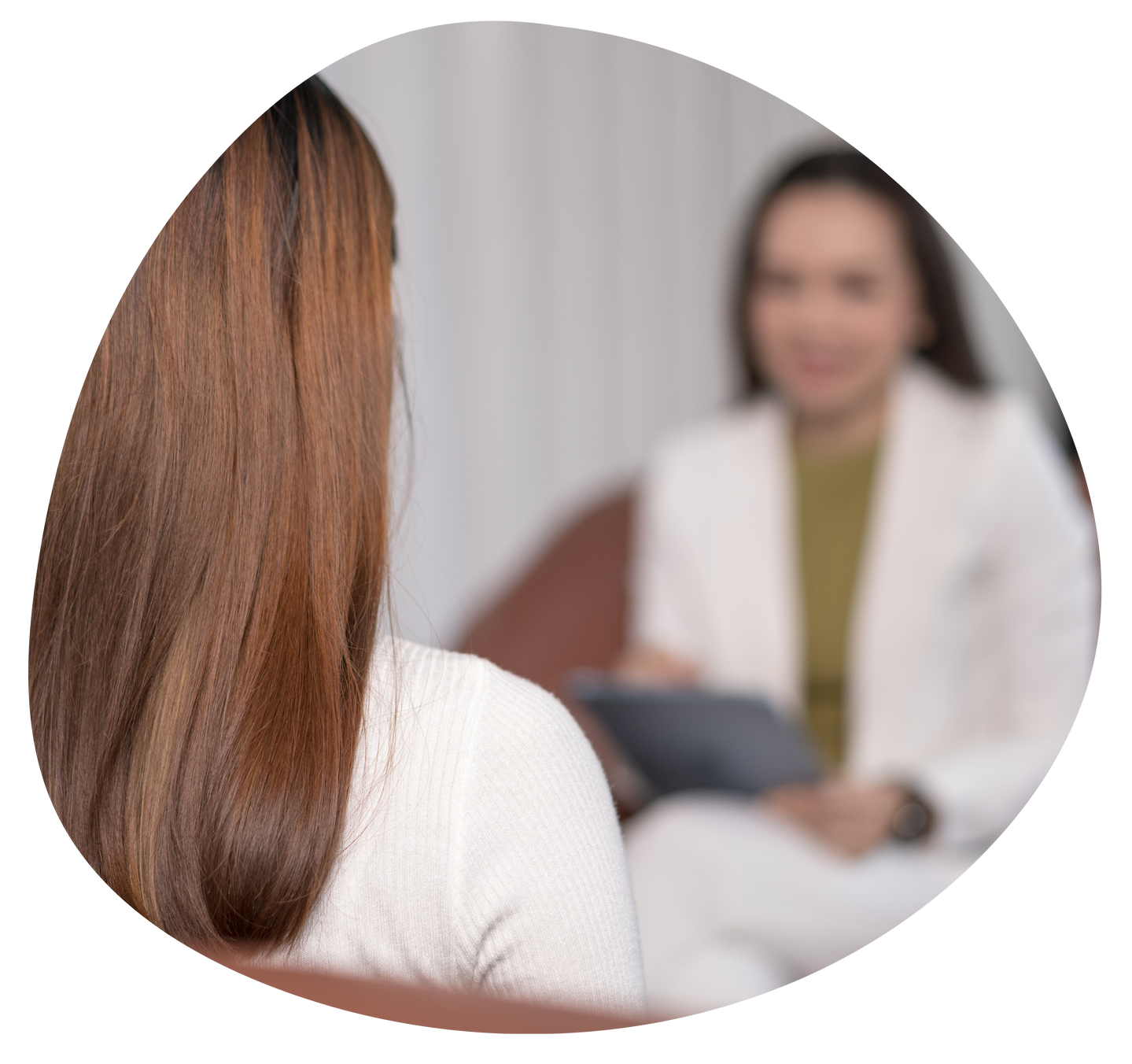 Two people in a counseling session, with one person seen from behind and the other blurred in the background.