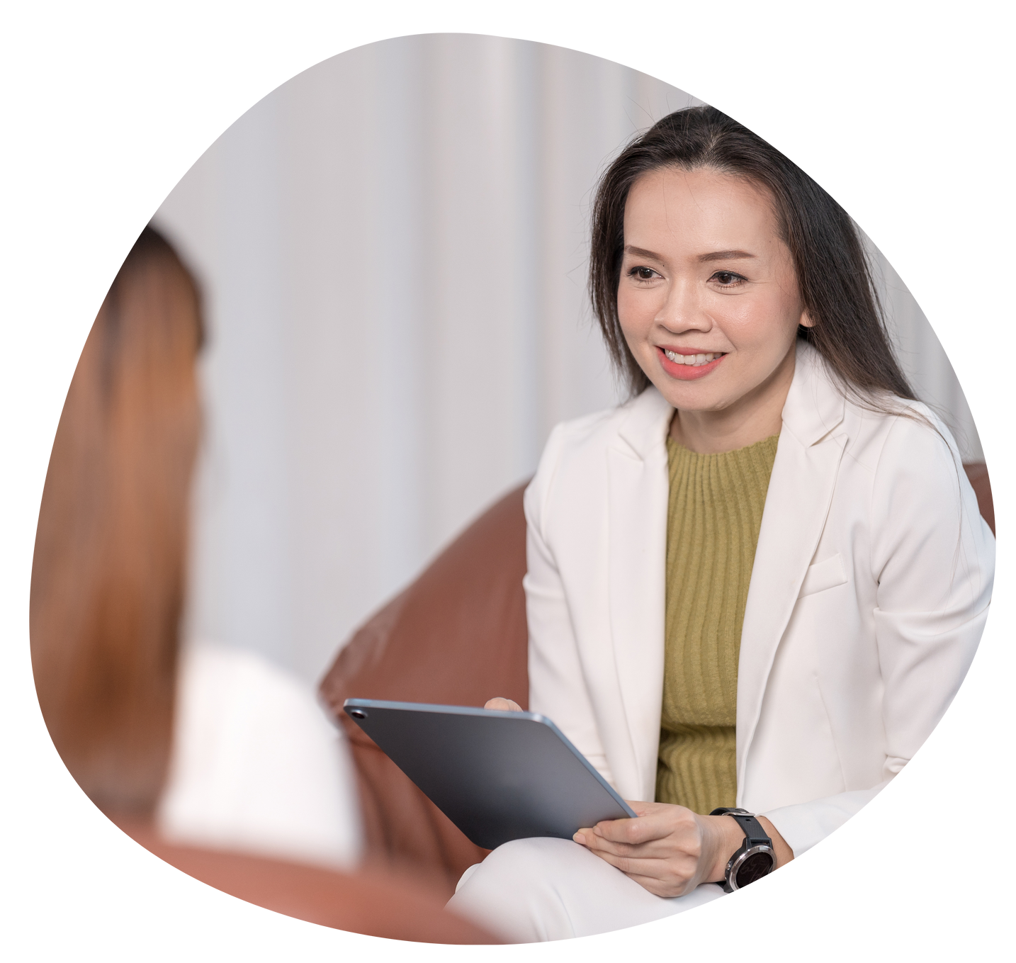 Doctor smiling and holding a tablet during a consultation in a bright clinic