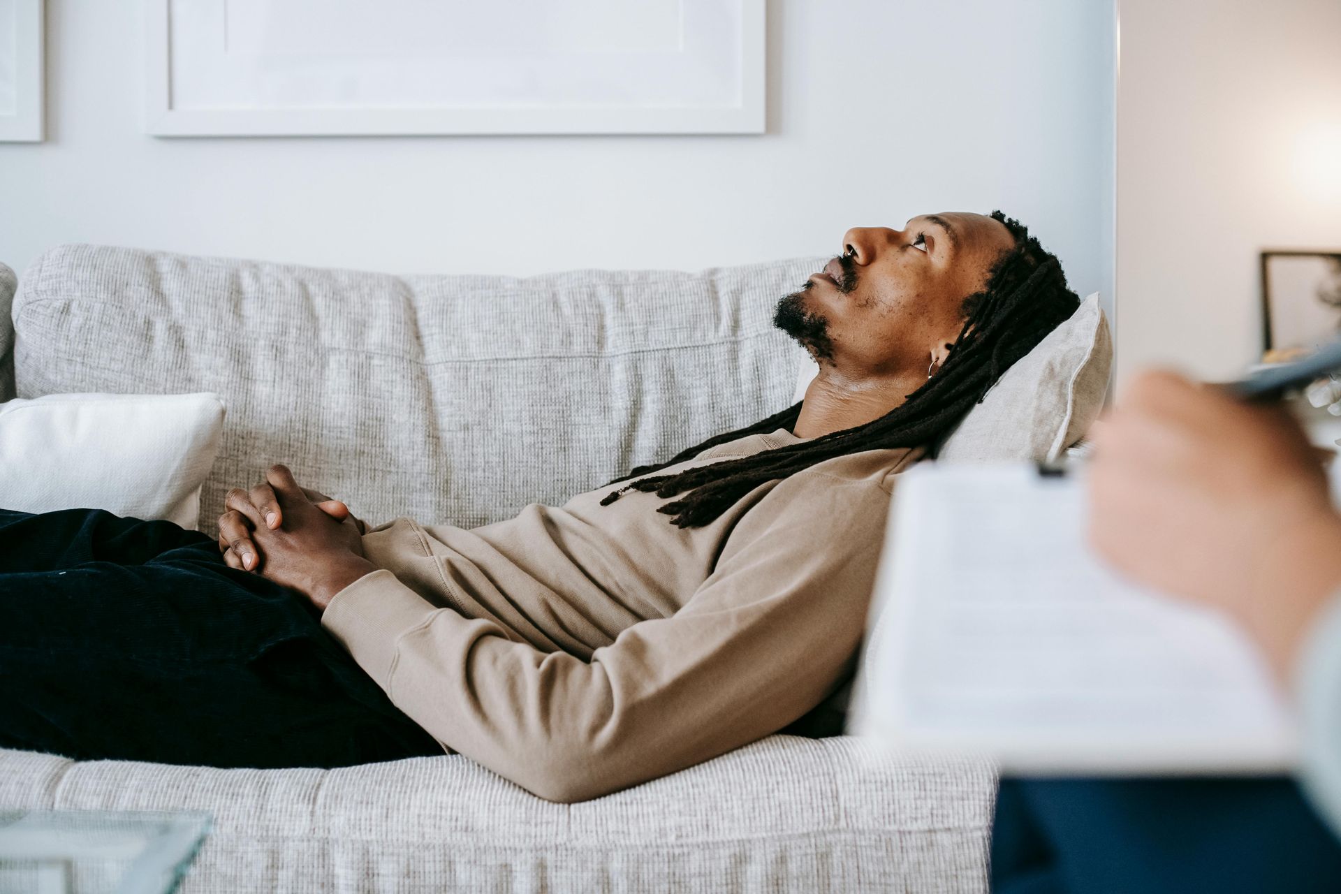 Person reclining on a couch, laughing in a bright living room.