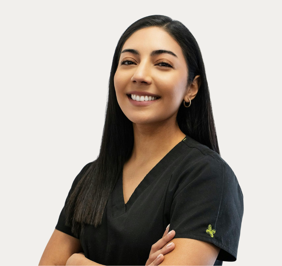 Smiling healthcare worker in black scrubs with arms crossed against a white background